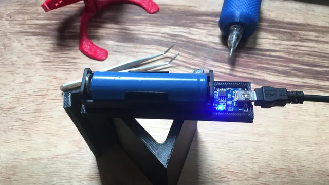 Bateria recarregável e placa eletrônica conectadas por cabo USB, sobre um suporte impresso