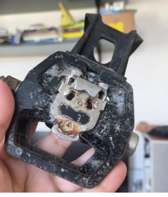 Pedal original desgastado, com a estrutura central danificada, segurado na mão